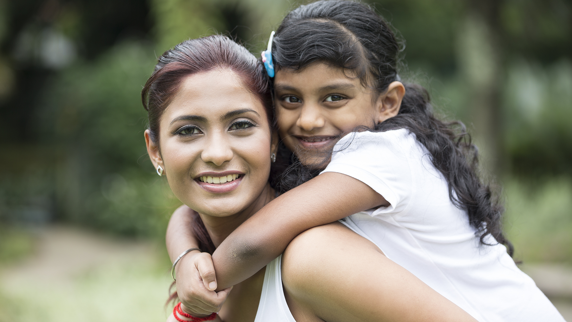 Photographer of a young girl smiling on her mother's back