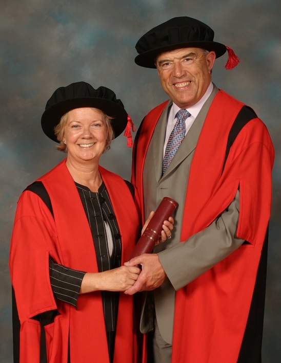 Image of a man and a woman holding hands and smiling into the camera